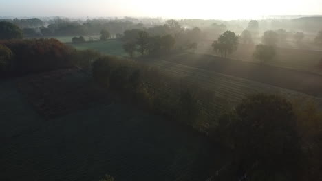 Flying-over-an-early-morning-foggy-landscape-during-sunrise