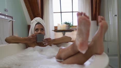 mixed race woman taking a bath and drinking coffee