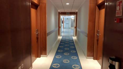 hotel corridor with room doors, carpet on the floor, trash can, fireproof systems with artificial led light