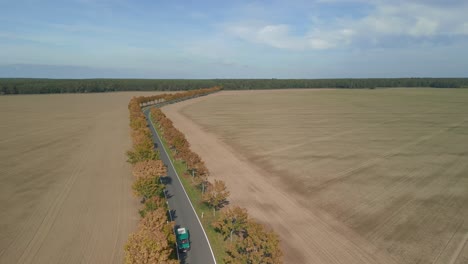 country road with cars through autumn fields