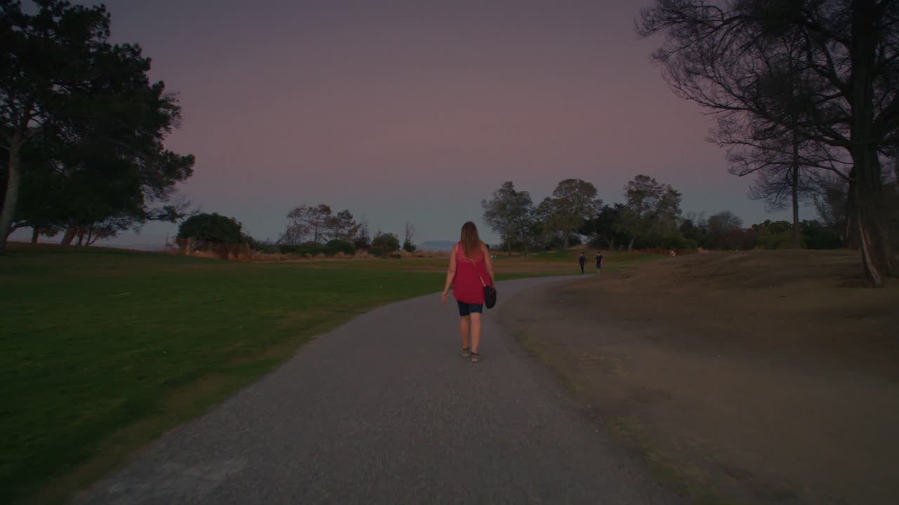 Steady shot closing in of woman walking from behind. In slow motion