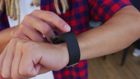 Mixed-race-man-with-dreadlocks-standing-in-the-street-using-smartwatch