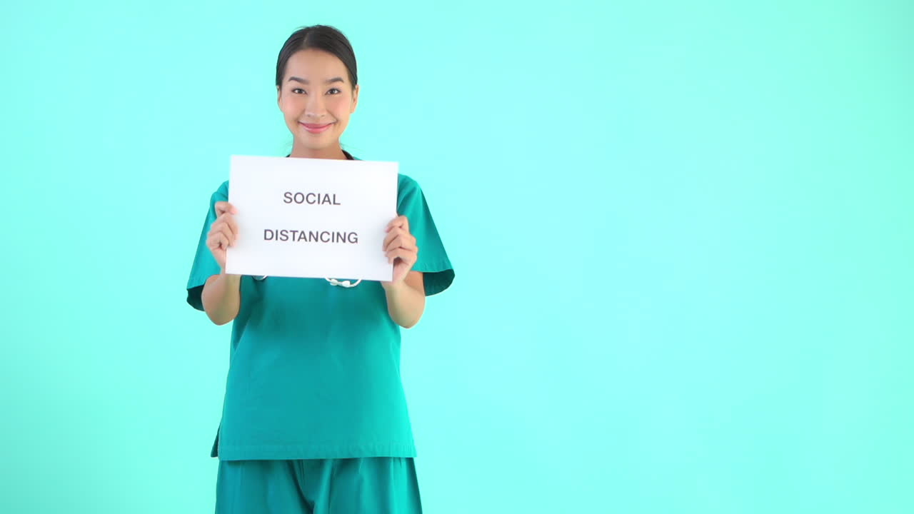 A young female medical professional holds up a sign reading Social Distancing. copy space