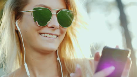 a woman of model appearance in sunglasses listens to music in the sun on vacation the rays of the su