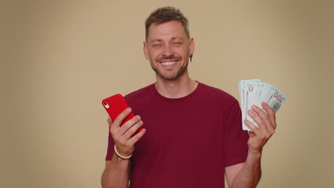 happy young man use smartphone rejoicing win, receiving money cash , success lottery jackpot luck