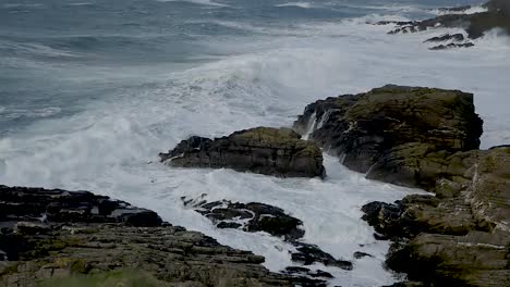 dramatic ocean waves crashing over rocks in slow motion at calf of man