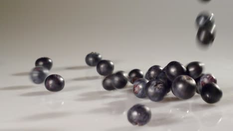 blueberries poured onto a white surface in slow motion