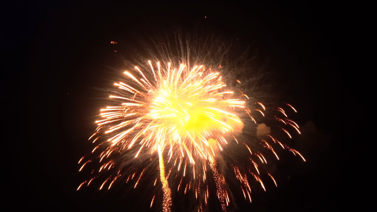 Esplosione di fuochi d'artificio dorati nel cielo notturno, con scie scintillanti e braci incandescenti che si irradiano verso l'esterno, centro intenso.