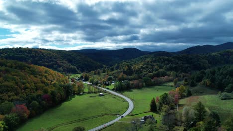 Drohnen-Hyper-Lapse-über-Dem-Ländlichen-Gebirgstal-Mit-Einem-Haus-Darunter,-Während-Dunkle-Wolken-über-Herbstbäumen-Vorbeiziehen