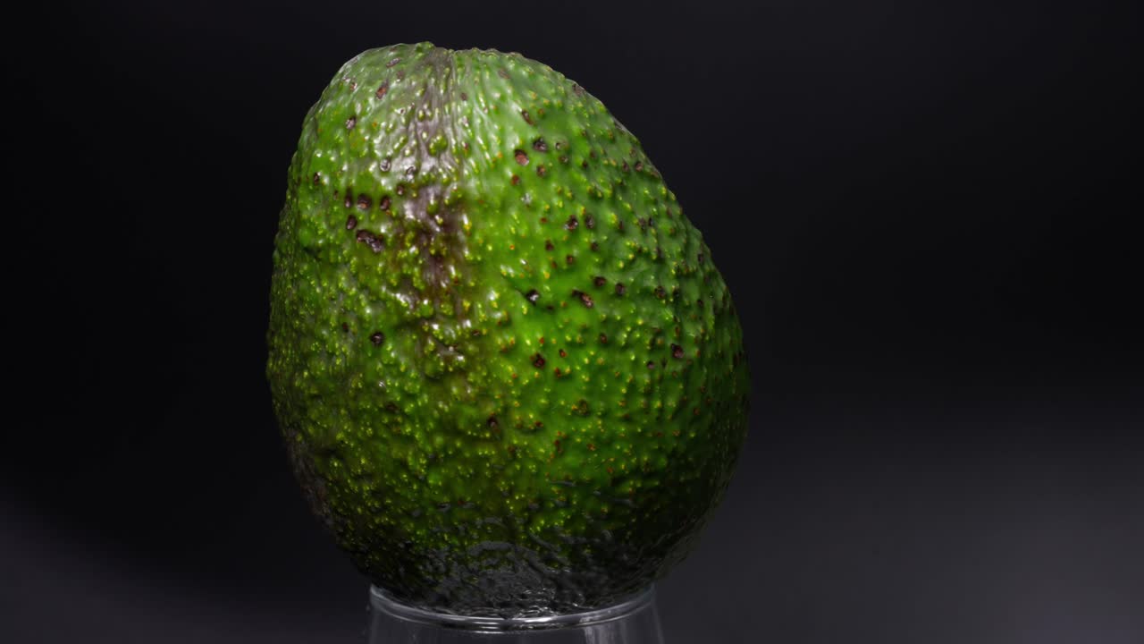 Slow motion shot of an avocado half rotating and a light turning of