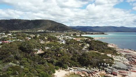 drone pan up over rural town and beautiful coastline with blue water in tasmania australia