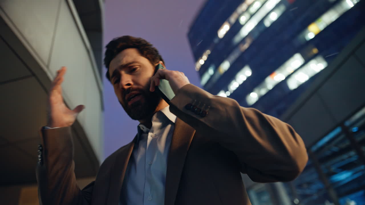 Ritratto di un uomo emotivo che parla al telefono in una zona commerciale serale