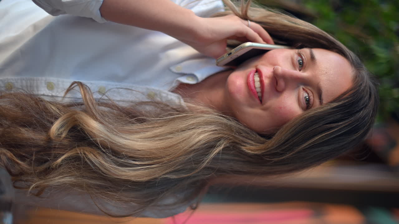 Happy woman talking on mobile phone in a restaurant, vertical screen