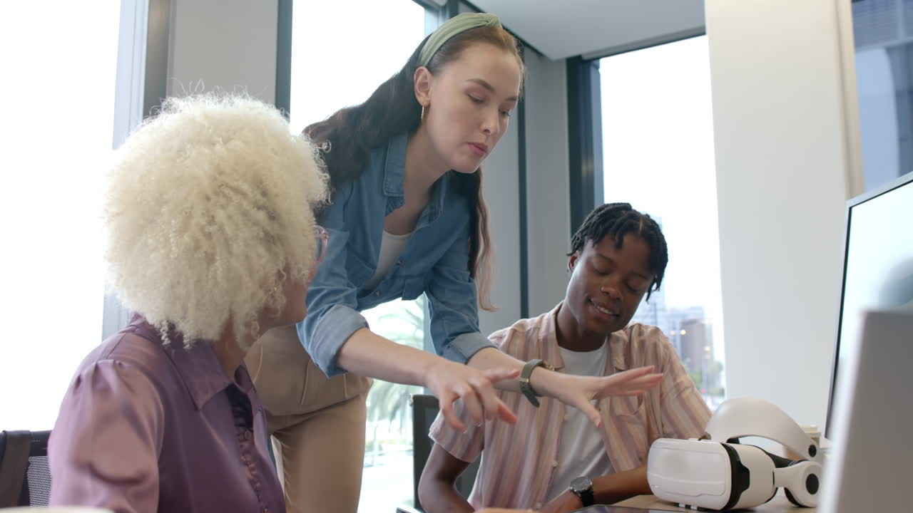 Discussing project, diverse team collaborating with laptop and VR headset in office