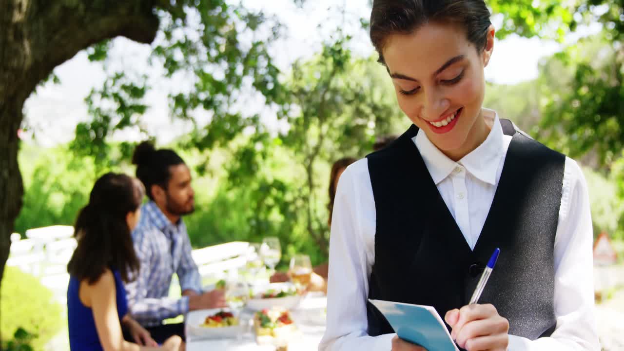 camarera escribiendo en un bloc de notas en un restaurante al aire libre