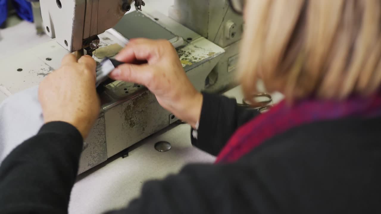 Caucasian woman using sewing machine in factory