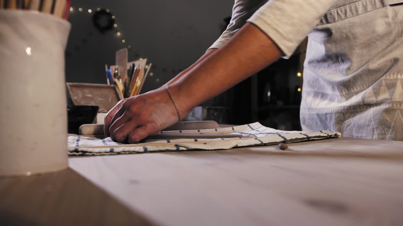 Pottery in the studio - young woman potter preparing a piece of clay