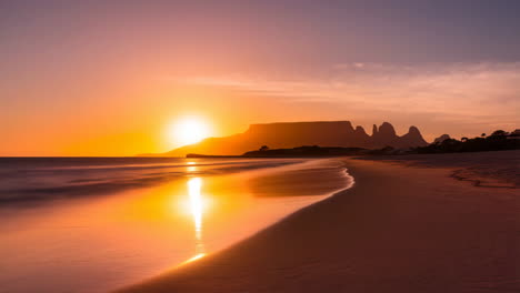 vibrant sunset over a serene beach with mountain silhouettes
