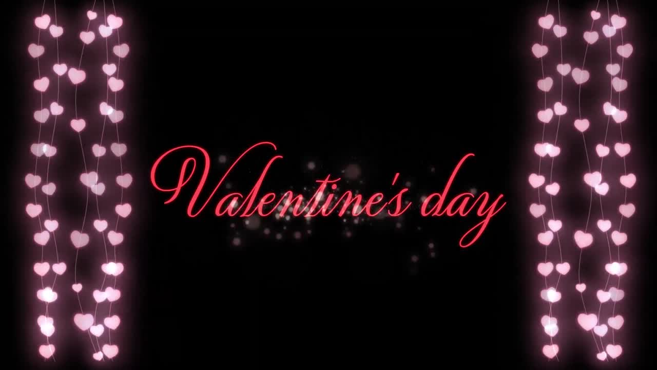 Animation of Valentine\'s Day written in pink letters on black background with two hearts garland