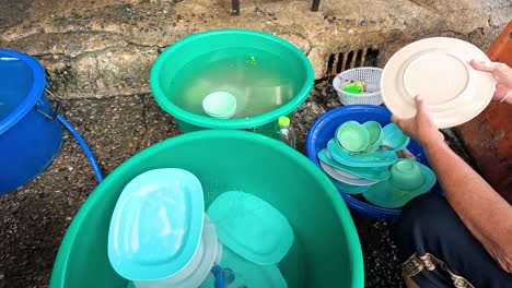 person washing dishes in a basin outdoors