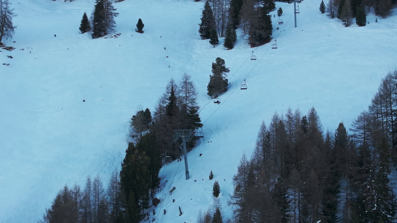 Drone aerial of ski lift in Chandolin, Switzerland. Chairlifts rise through snowy slopes and alpine forest creating a classic winter tourism and ski resort scene for travel and cinematic stock footage