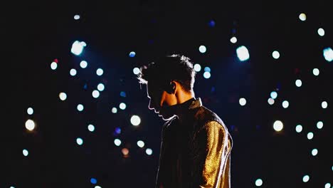 joven cantante masculino con una chaqueta brillante actuando en el escenario, iluminado por focos con confeti cayendo a su alrededor, creando una atmósfera mágica