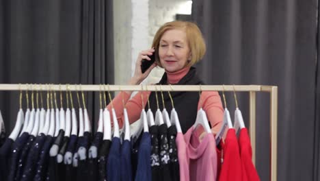 una anciana de apariencia europea elige ropa en una tienda. compras y compras
