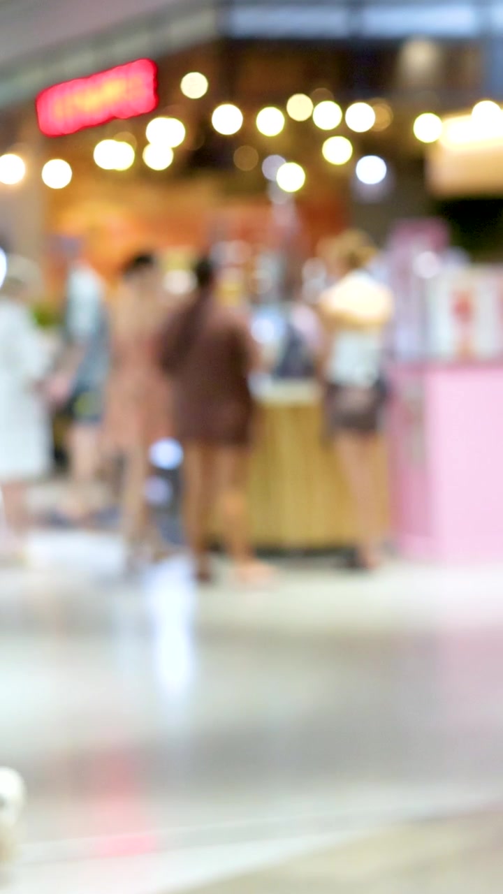 Clienti si muovono in un supermercato affollato con illuminazione brillante e colori vivaci, catturando un'atmosfera allegra e dinamica.