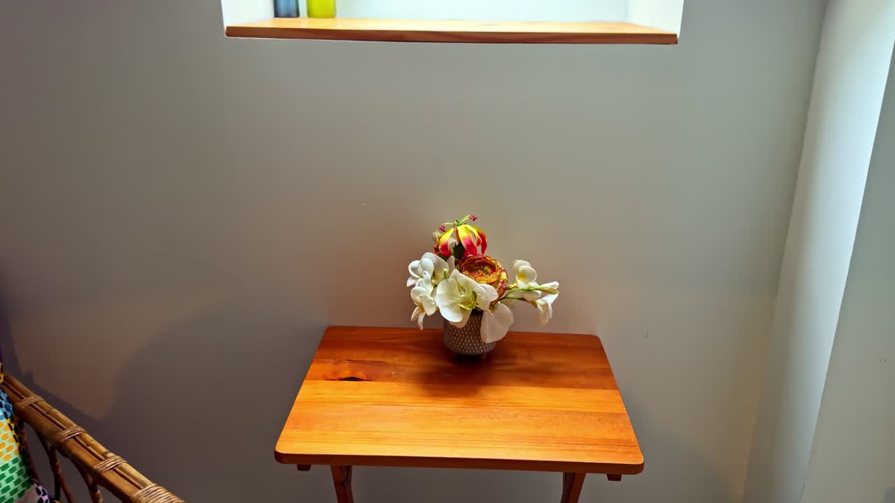 A cozy attic room features a vibrant floral arrangement on a wooden table beneath a skylight. Ideal for home decor or interior design concepts