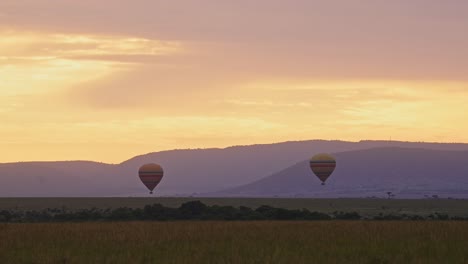 hot air balloon flight ride, flying over masai mara savanna landscape in africa at sunrise with dramatic orange sunset sky and clouds, beautiful savannah scenery and mountains