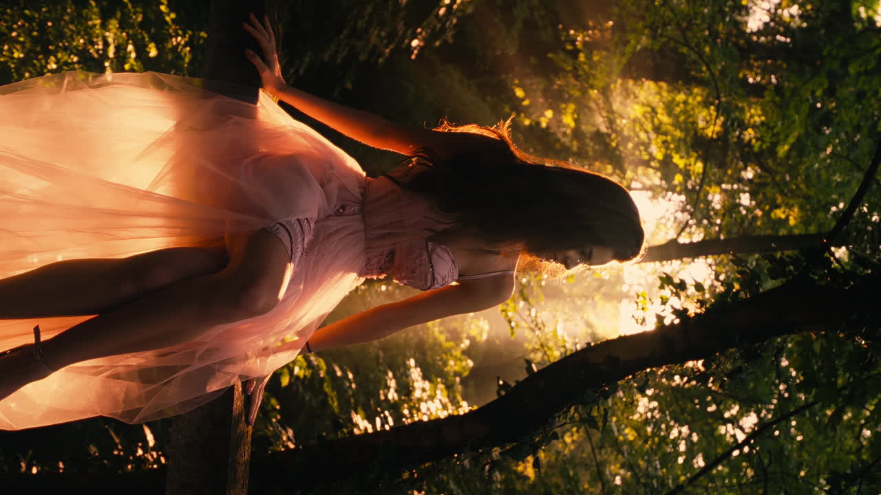 젊은 갈색 백인 모델 소녀가 식물원 태양빛, 수직 비디오, 분홍색 긴 드레스를 입고 포즈를 취합니다