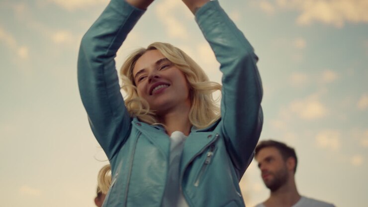 Giovane donna che balla a una festa sul tetto al tramonto. Ragazza gioiosa che si diverte all'aperto.