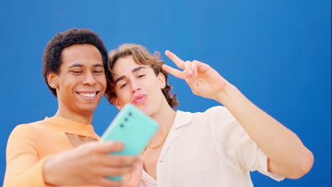 multiracial friends taking a selfie next to a blue wall