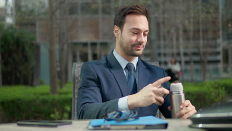 businessman drinking coffee while sitting in a park