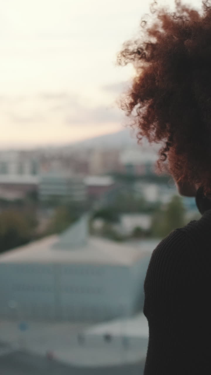 Woman with Afro gazing at cityscape during sunset