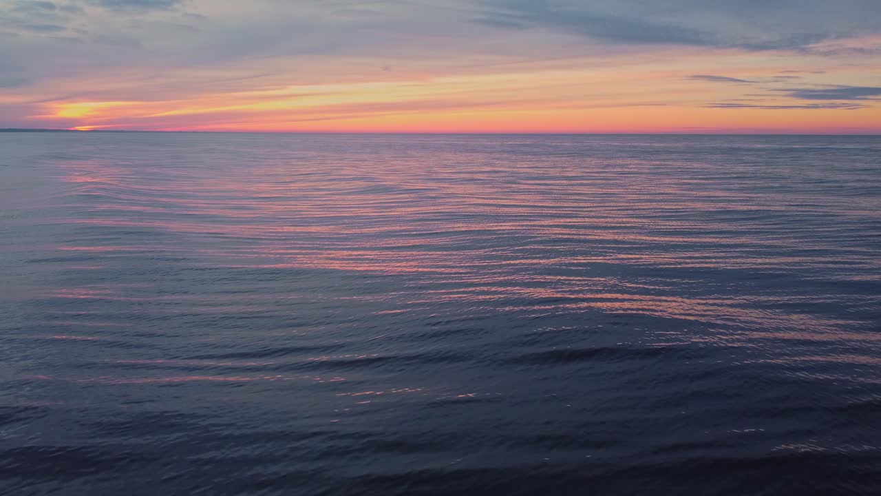 Calm sea water surface and orange sunset or sunrise sky, static view