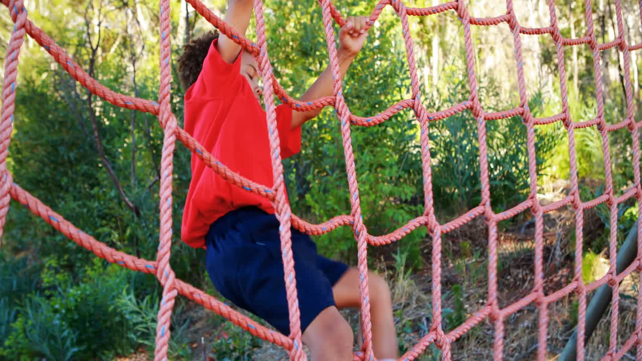 Determined boy climbing a net during obstacle course
