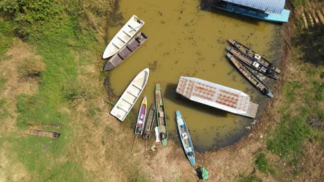 Una-Filmación-Aérea-Constante-De-Un-Recorrido-En-Barco-En-Bueng-Boraphet,-Nakhon-Sawan,-Tailandia,-Que-Revela-Barcos-Amarrados-En-Una-Estación-Mientras-Un-Gran-Pontón-Se-Está-Moviendo