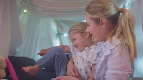 mother and young daughter with digital tablet in homemade camp in child's bedroom at home - shot in slow motion