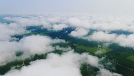 Aerial Shot Flying Over Forest and Farmland Hidden Under Clouds in Scenic View