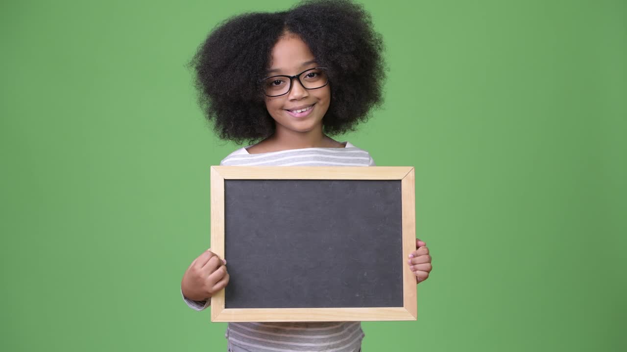 Young cute African girl with Afro hair holding blackboard