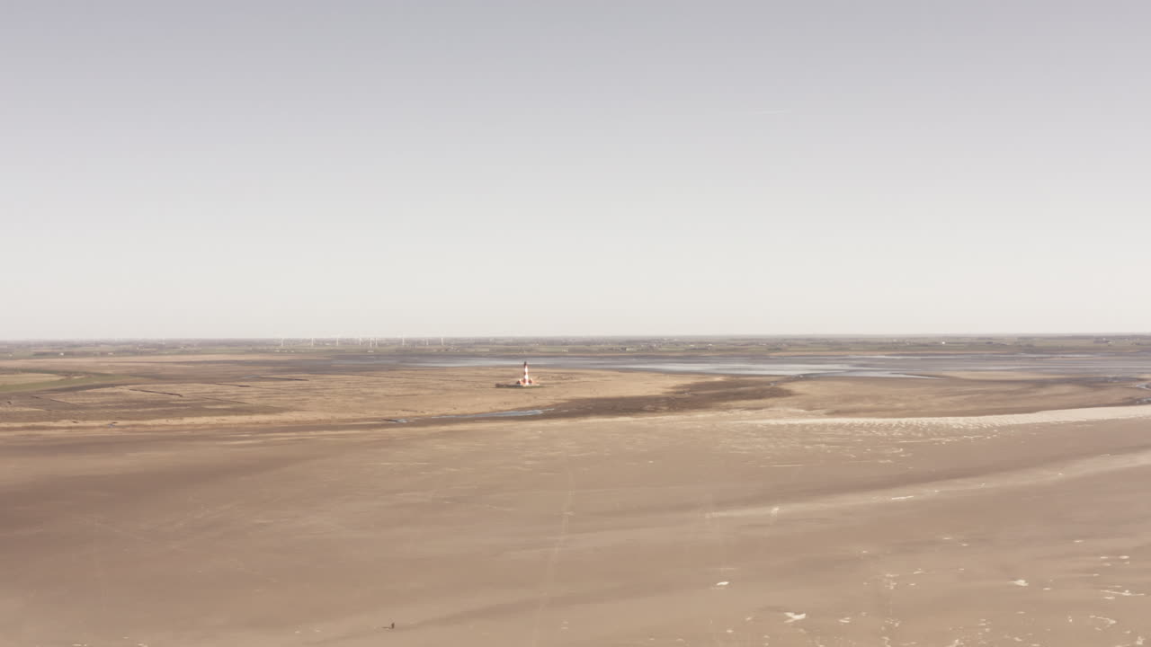 infinite wideness, drone ascent, panoramic view of a beach and tideland. Beacon at the horizon at the background
