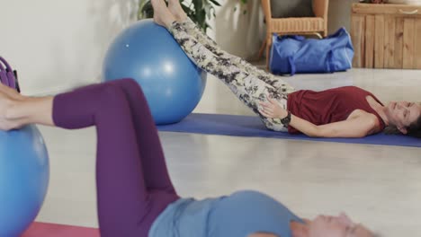 una mujer caucásica senior usando una pelota de ejercicio con una entrenadora de pilates, sin alteración, en cámara lenta.