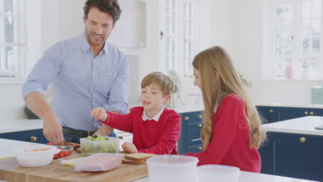 Padre-Ayudando-A-Niños-Con-Uniforme-Escolar-A-Preparar-Un-Sándwich-Saludable-Para-El-Almuerzo-Para-Llevar-En-La-Cocina
