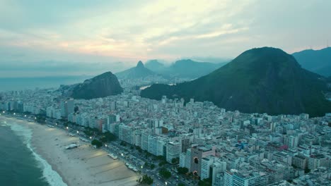 vuela sobre el establecimiento de río de janeiro con nublado y puesta de sol épica con montañas en el fondo brasil