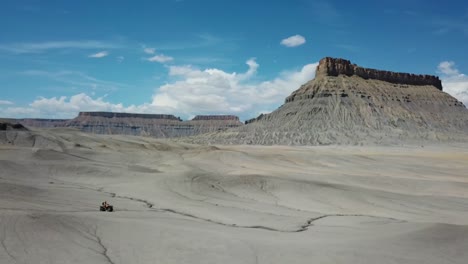 vehículo quad atv moviéndose en el paisaje seco del desierto de utah y butte de fábrica, vista aérea