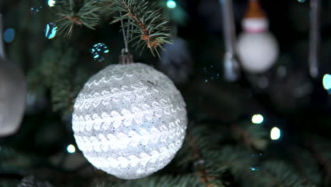 bola blanca con adorno texturizado colgando del árbol de navidad por la noche