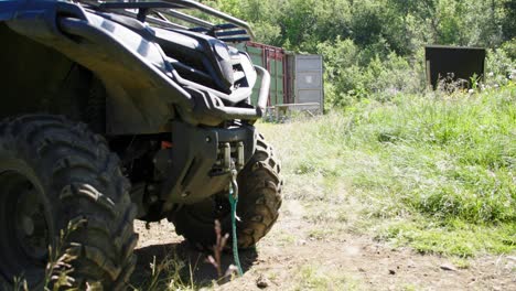 front of all terrain 4x4 quadbike standing in grass field with containers in background