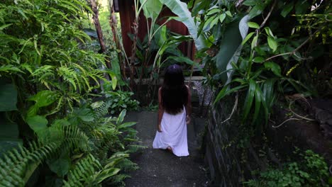 slow motion of asian girl in white dress walking downstairs through a garden in bali indonesia