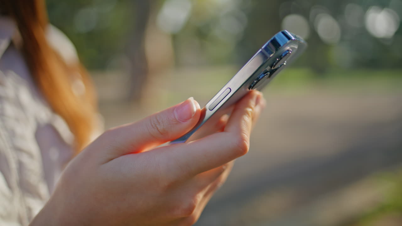 manos de primer plano sosteniendo un teléfono inteligente destacando la comunicación digital en el parque.